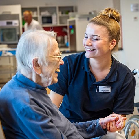 Mitarbeiterin pflegt lachende Seniorin